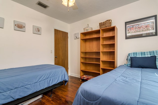 bedroom featuring visible vents, a textured ceiling, wood finished floors, baseboards, and ceiling fan