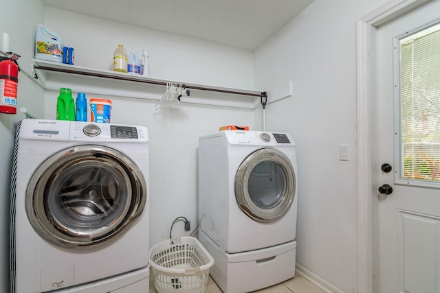 laundry area with washer and clothes dryer, laundry area, tile patterned floors, and baseboards