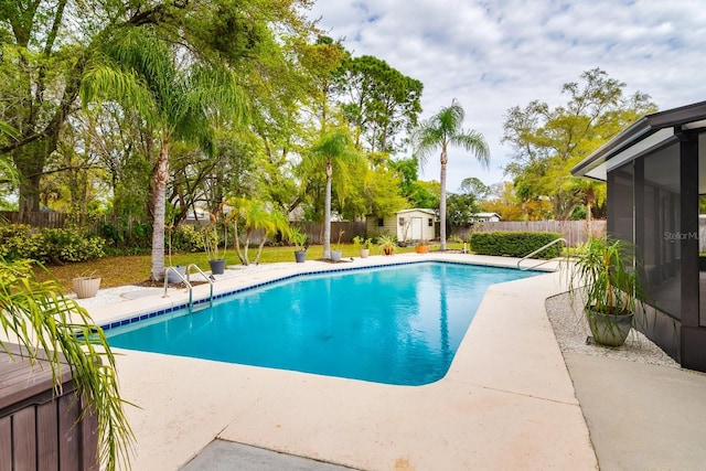 view of pool with a patio, a fenced in pool, a fenced backyard, an outdoor structure, and a storage shed