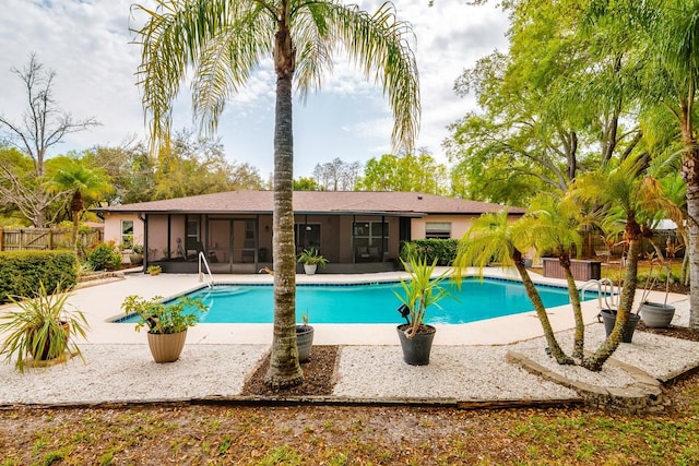 outdoor pool with a patio, fence, and a sunroom