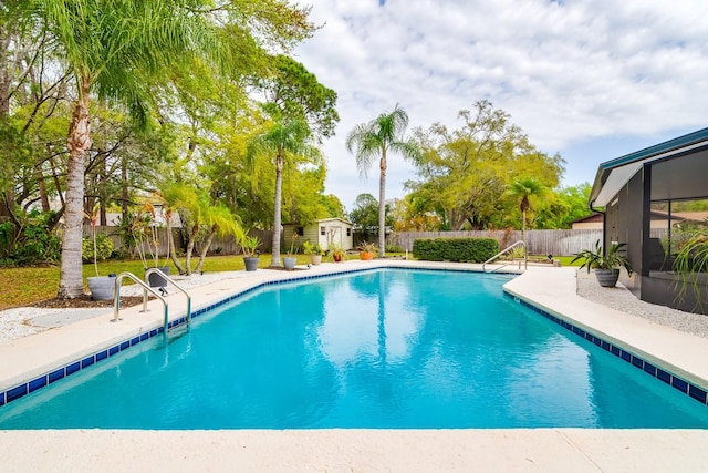 view of swimming pool featuring a storage unit, a fenced in pool, an outbuilding, and a fenced backyard