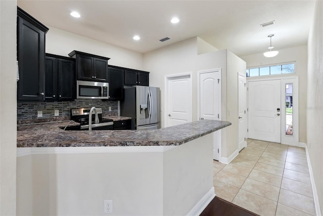 kitchen featuring dark countertops, a peninsula, stainless steel appliances, and dark cabinets