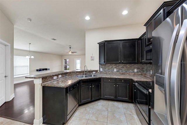 kitchen with a sink, dark stone counters, dark cabinetry, and stainless steel appliances