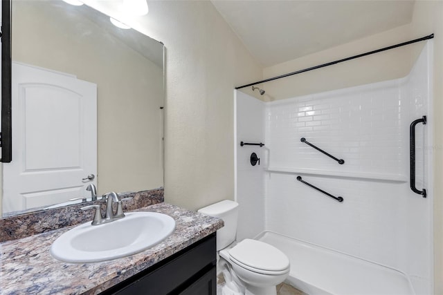 bathroom featuring vanity, toilet, a textured wall, and walk in shower