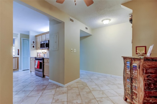 corridor featuring light tile patterned flooring, baseboards, visible vents, and a textured ceiling