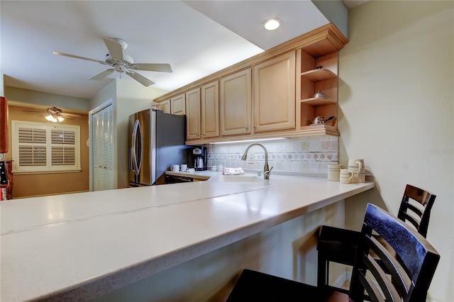 kitchen featuring a sink, tasteful backsplash, freestanding refrigerator, light countertops, and ceiling fan