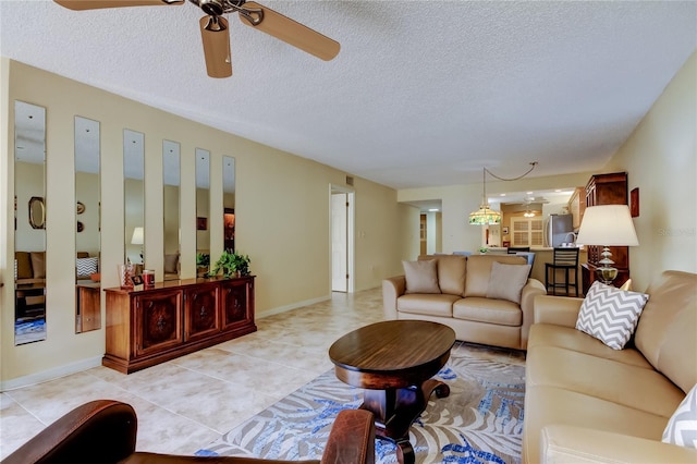 living area with ceiling fan, light tile patterned flooring, baseboards, and a textured ceiling