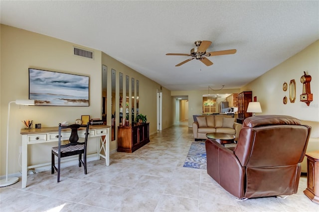 living room with light tile patterned floors, visible vents, a textured ceiling, and a ceiling fan