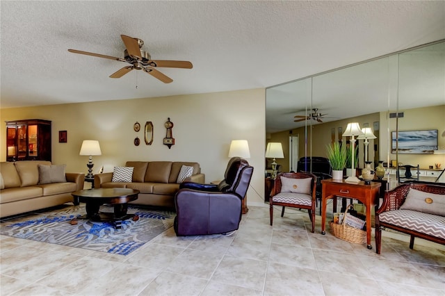 living area with light tile patterned floors, a ceiling fan, and a textured ceiling