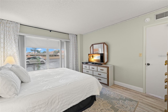 bedroom featuring visible vents, a textured ceiling, baseboards, and light wood-style floors