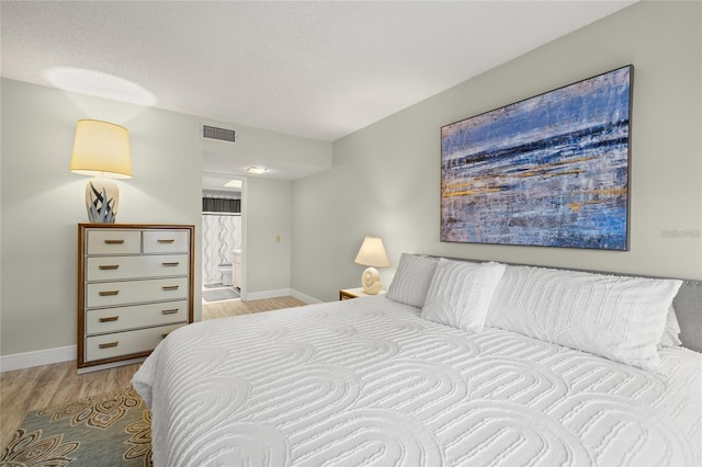 bedroom featuring visible vents, baseboards, a textured ceiling, and light wood finished floors