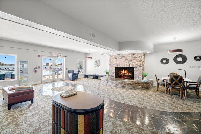 living area with a brick fireplace, baseboards, and a textured ceiling