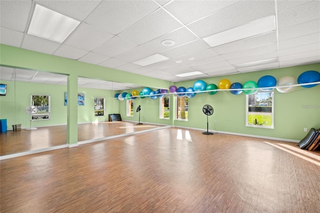 exercise area featuring wood finished floors, baseboards, and a drop ceiling