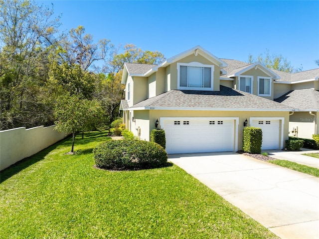 view of front facade with stucco siding, a front lawn, fence, roof with shingles, and concrete driveway