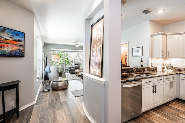 kitchen with dark stone countertops, wood finished floors, visible vents, a sink, and stainless steel dishwasher