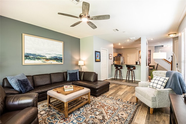 living area featuring visible vents, wood finished floors, stairway, baseboards, and ceiling fan