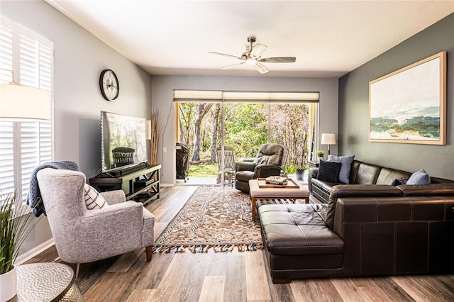 living room with baseboards, ceiling fan, and wood finished floors