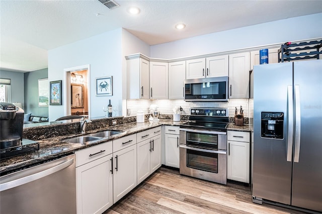 kitchen featuring a sink, visible vents, appliances with stainless steel finishes, and dark stone countertops