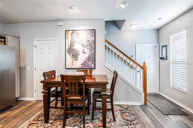 dining space featuring baseboards, wood finished floors, and stairs