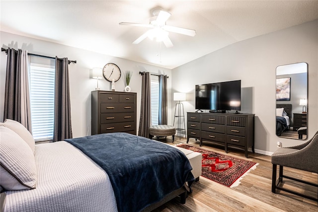 bedroom with ceiling fan, baseboards, wood finished floors, and vaulted ceiling