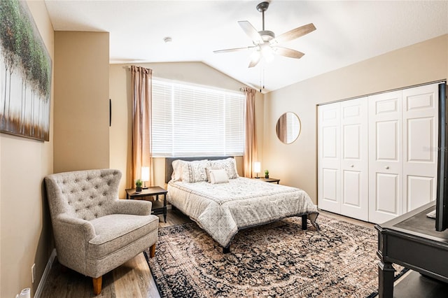 bedroom featuring wood finished floors, a closet, baseboards, lofted ceiling, and ceiling fan