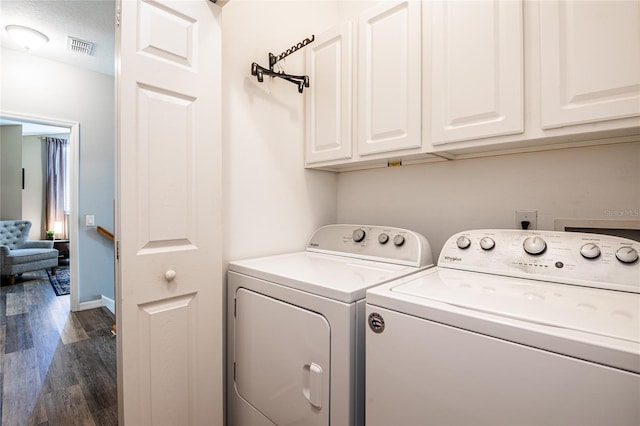 washroom with baseboards, visible vents, washing machine and clothes dryer, cabinet space, and dark wood-style flooring