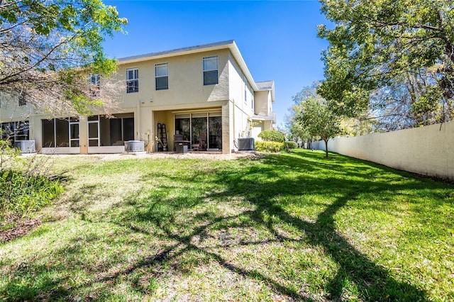 rear view of property with cooling unit, a lawn, fence, and a sunroom