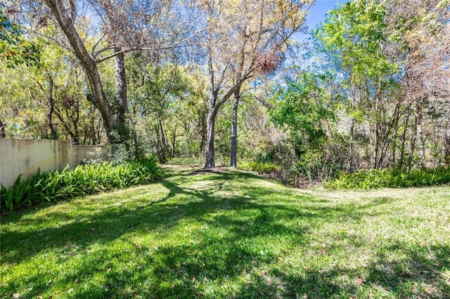 view of yard with a wooded view and fence