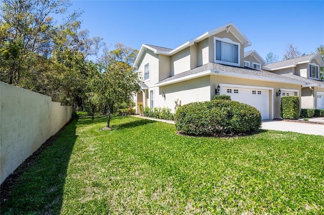 view of side of home featuring fence, a lawn, driveway, and stucco siding