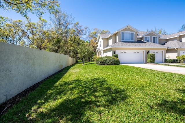 exterior space with fence, stucco siding, a garage, a yard, and driveway