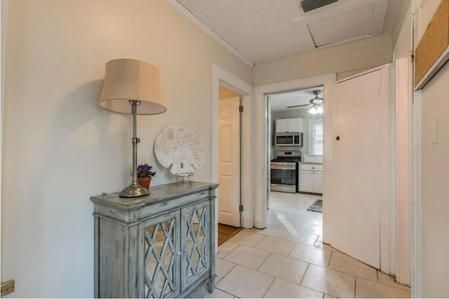 hallway featuring attic access, light tile patterned flooring, and visible vents