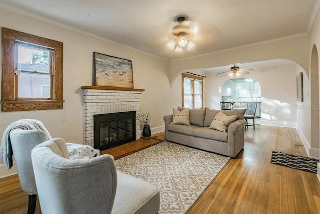 living room with baseboards, crown molding, a fireplace, and hardwood / wood-style flooring