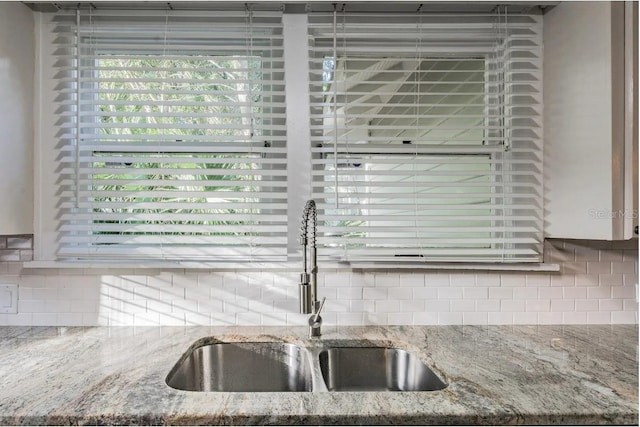 details with light stone countertops, backsplash, and a sink