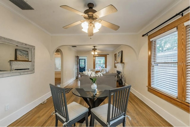 dining space featuring arched walkways, baseboards, and wood finished floors