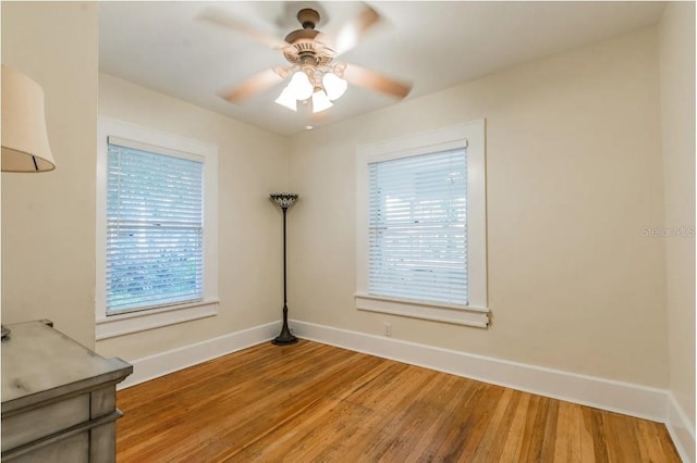 spare room featuring ceiling fan, baseboards, and wood finished floors