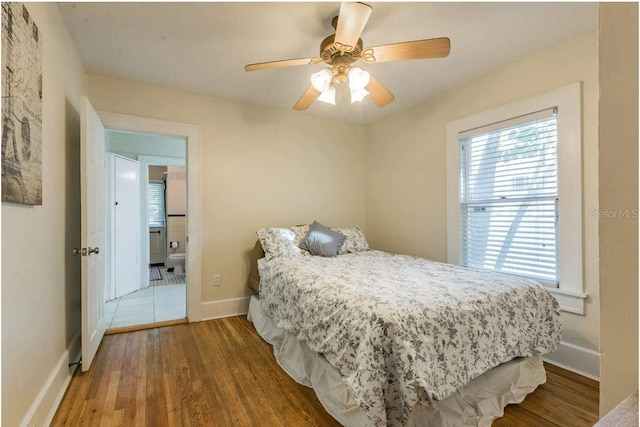 bedroom with a ceiling fan, wood finished floors, and baseboards