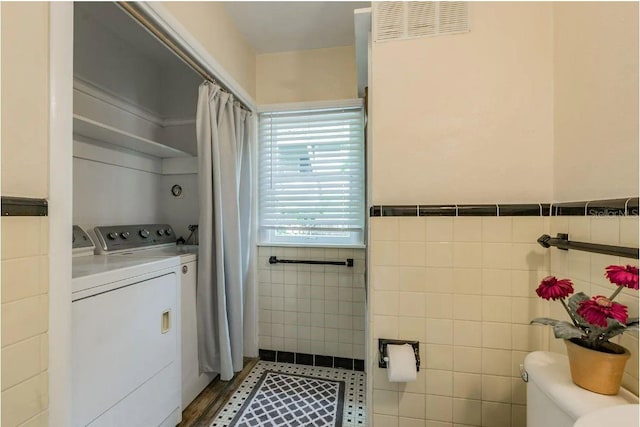 bathroom featuring visible vents, curtained shower, tile walls, toilet, and independent washer and dryer