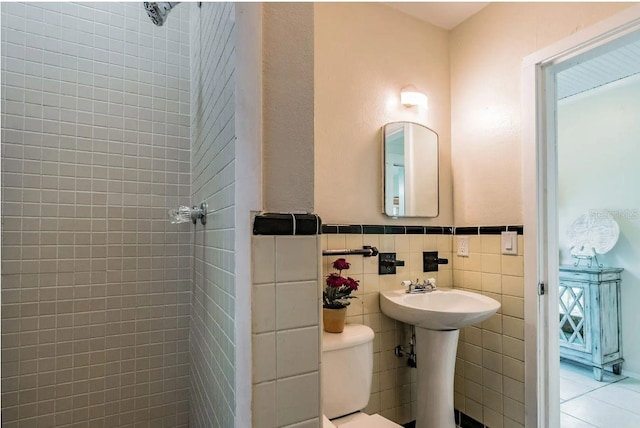 bathroom featuring tile patterned floors, wainscoting, toilet, and tile walls