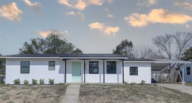 view of front of house with stucco siding, a carport, and concrete driveway