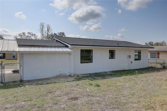 view of side of home featuring stucco siding, a lawn, a standing seam roof, fence, and metal roof