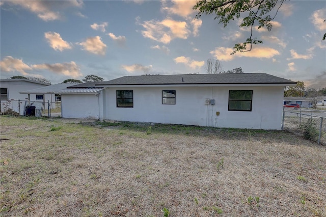 rear view of property featuring stucco siding, a yard, and fence