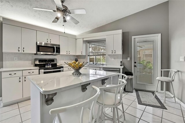 3943 W Fieldwood Ct, Lecanto, FL 34461 - kitchen featuring appliances with stainless steel finishes, light tile patterned floors, lofted ceiling, backsplash, and a textured ceiling