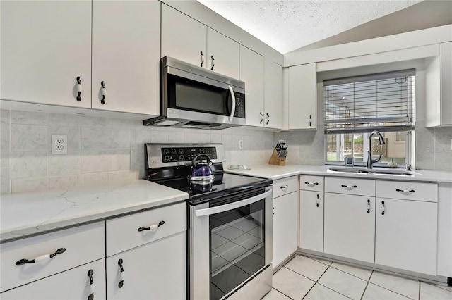 3943 W Fieldwood Ct, Lecanto, FL 34461 - kitchen with stainless steel appliances, a sink, backsplash, white cabinetry, and vaulted ceiling