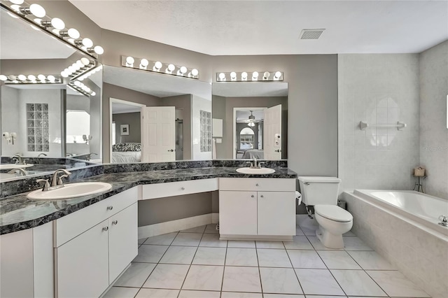3943 W Fieldwood Ct, Lecanto, FL 34461 - ensuite bathroom with tiled tub, two vanities, tile patterned floors, toilet, and ceiling fan