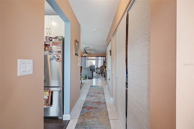 hall featuring baseboards and light tile patterned flooring