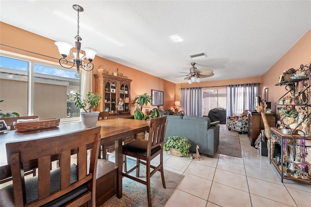 dining space featuring light tile patterned floors, visible vents, and ceiling fan with notable chandelier