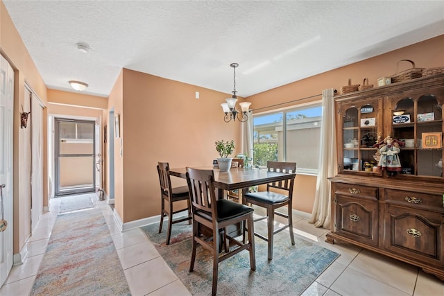 dining area featuring baseboards, a textured ceiling, a chandelier, and light tile patterned flooring