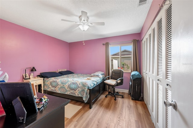 bedroom featuring a ceiling fan, wood finished floors, visible vents, a closet, and a textured ceiling