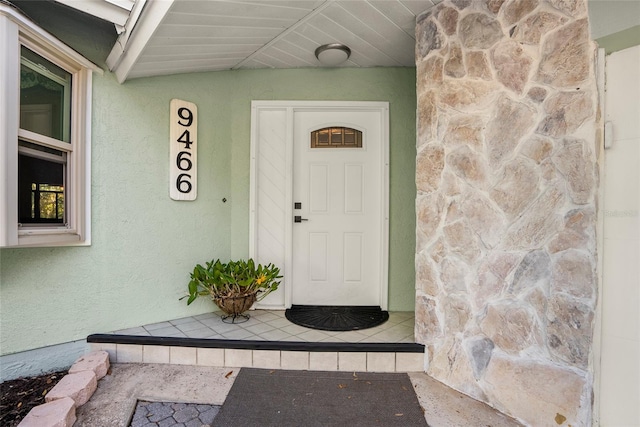 property entrance with stucco siding and stone siding