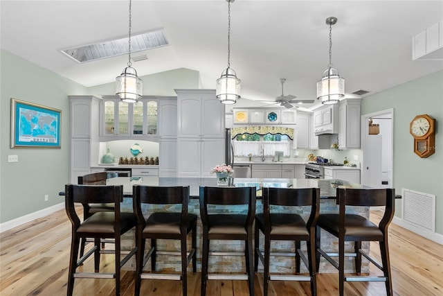 kitchen with light wood-type flooring, visible vents, a breakfast bar area, and stainless steel appliances